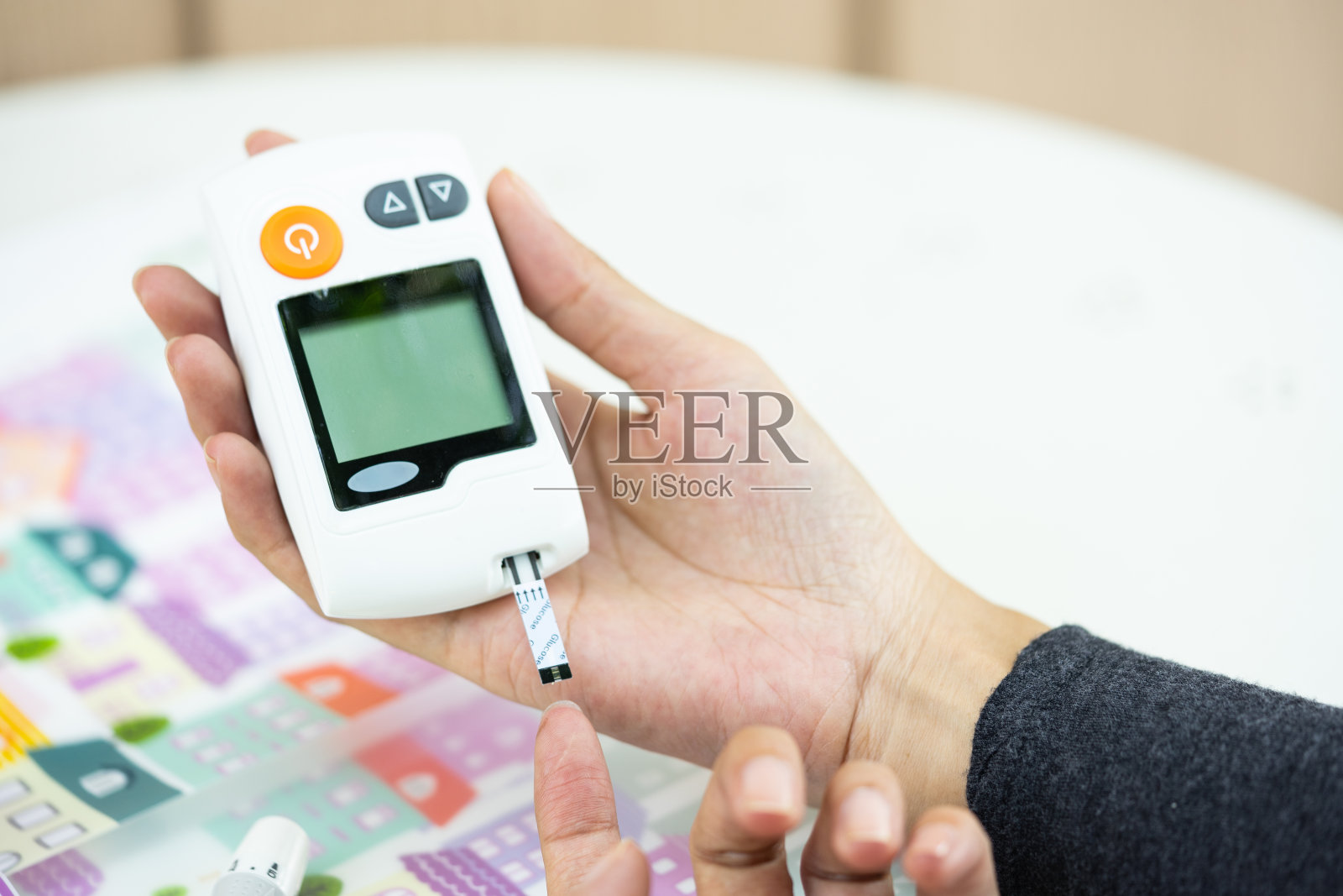 近亚洲男子的手使用柳叶刀的手指检查血糖水平的血糖仪，医疗保健和检查，糖尿病，血糖，和人的概念照片摄影图片