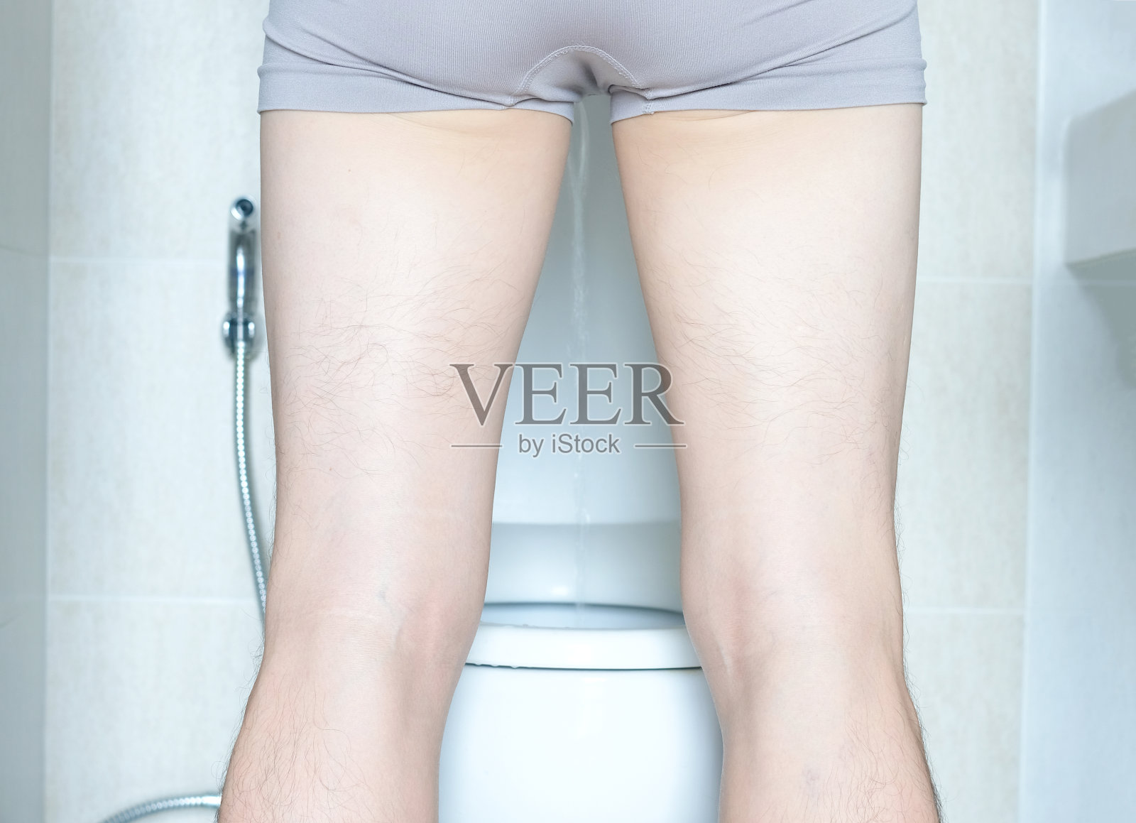 后视图男人站在家里厕所里对着马桶撒尿。健康的概念照片摄影图片