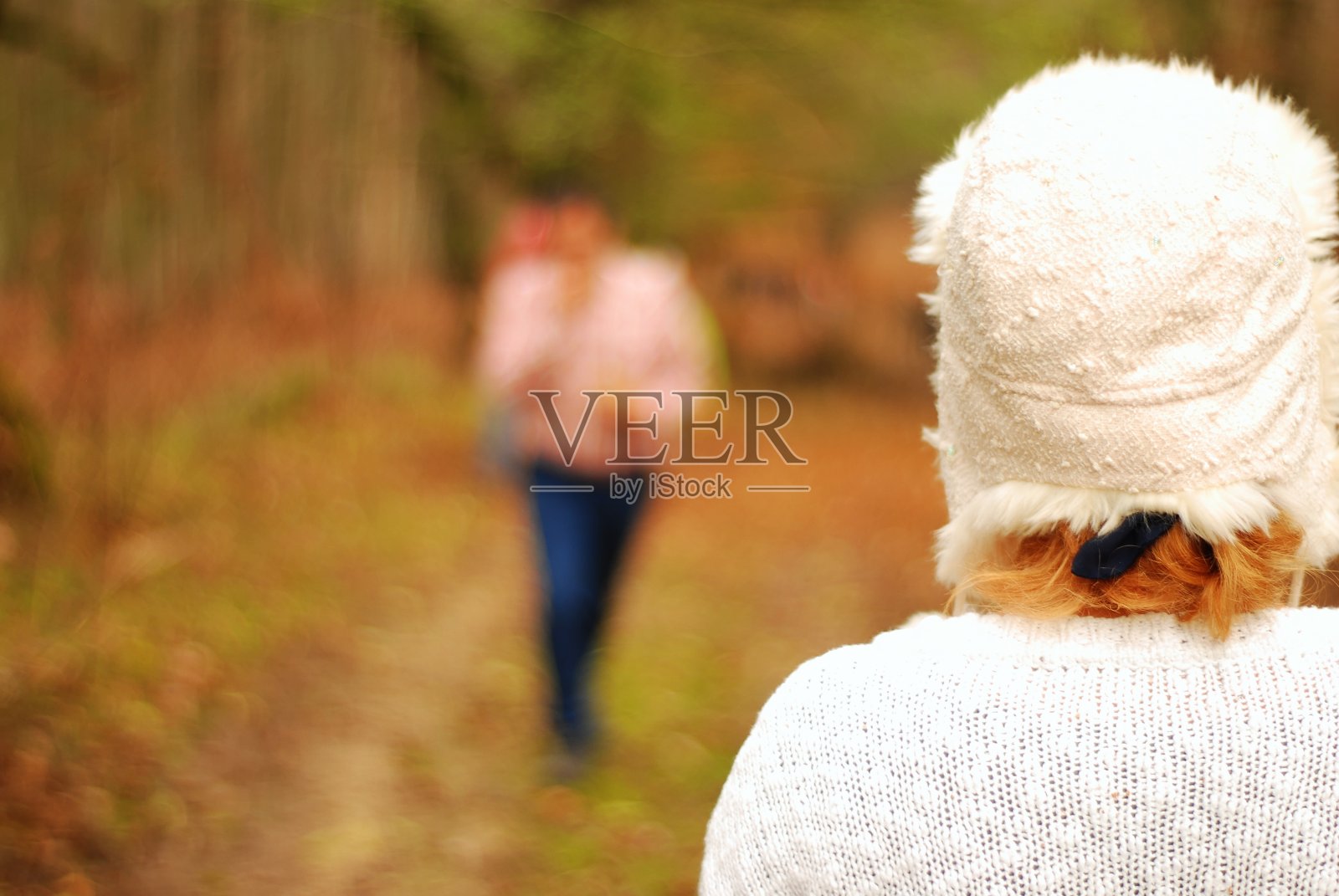 一个穿着白色衣服的女人背对着在泥泞的路上照片摄影图片