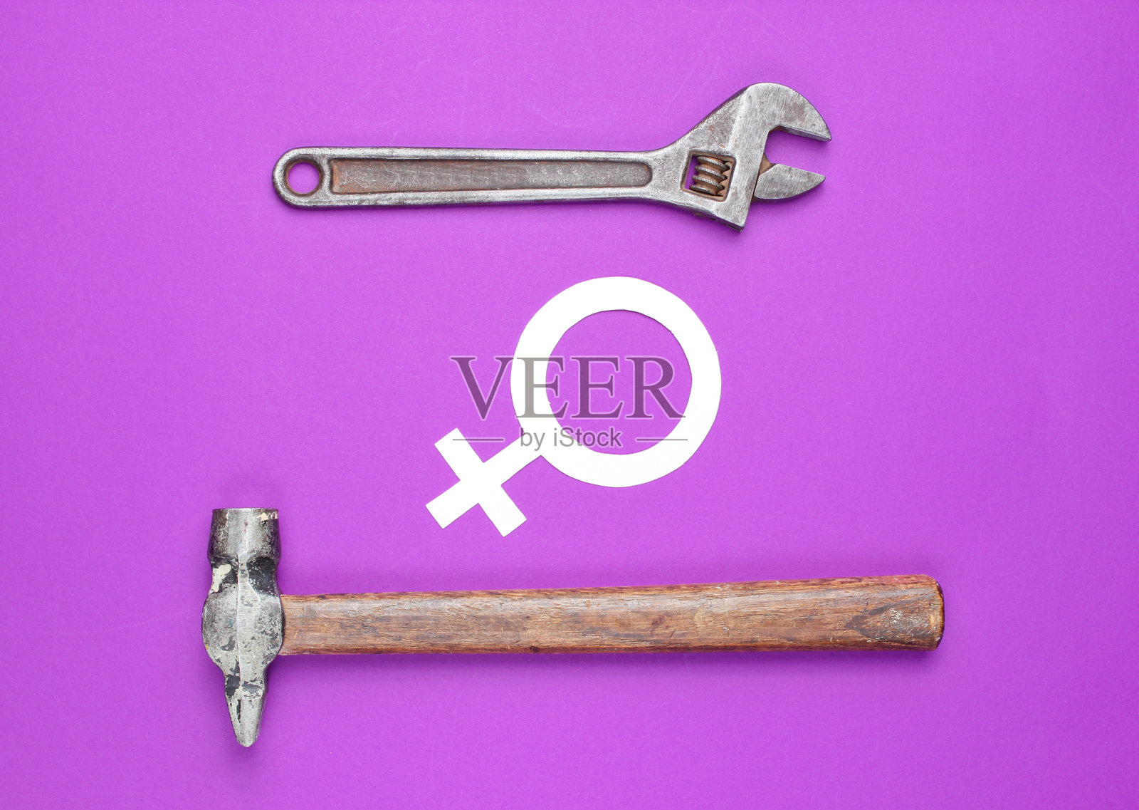 妇女选择男性工作。女权主义。性别平等。紫色背景上的锤子、扳手和女权主义象征。顶视图照片摄影图片