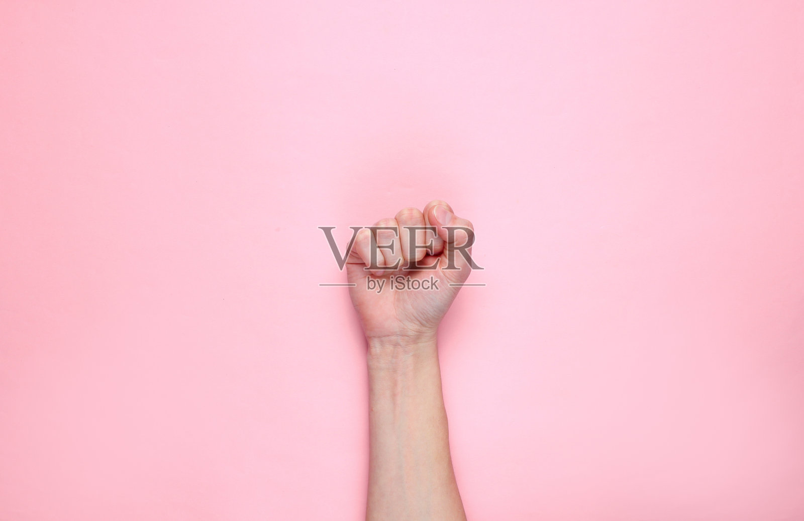 女权主义。女性拳头在粉红色的背景。前视图中,极简主义照片摄影图片