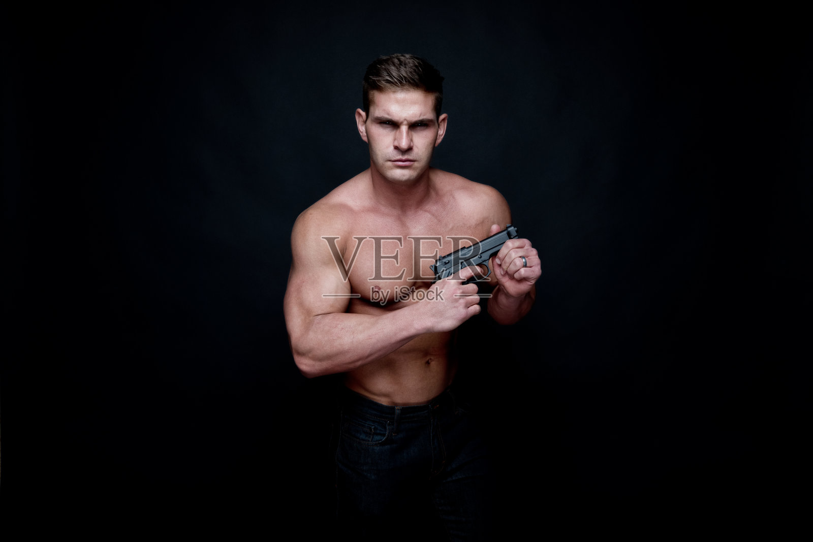 赤裸上身的肌肉男拿着一把手枪照片摄影图片