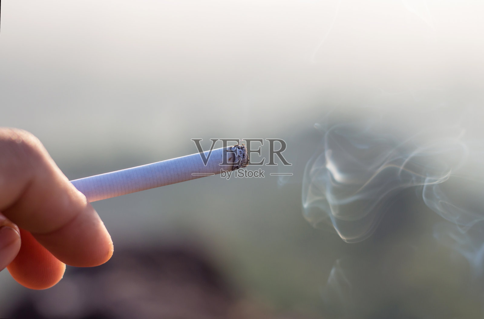 手握着燃烧着的香烟。照片摄影图片