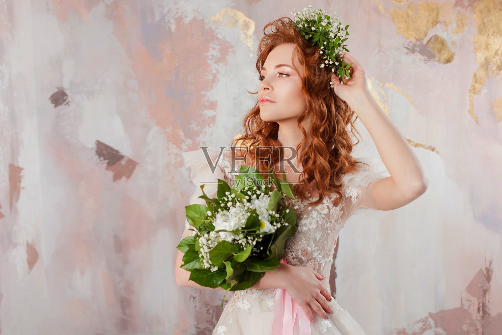 一个年轻美丽的女人的肖像穿着婚纱与花环和鲜花的花束。照片摄影图片