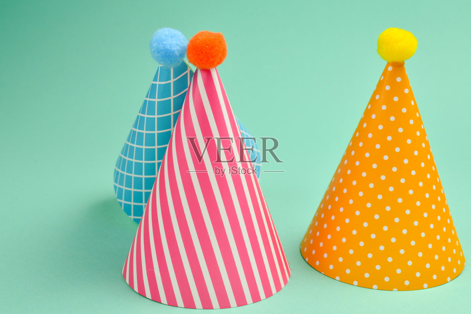 绿色背景上的彩色生日帽。照片摄影图片