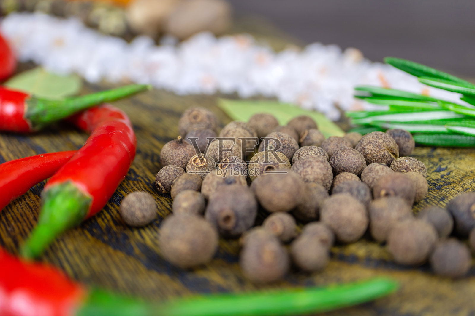 砧板上的东方香料:迷迭香，红辣椒和多香果。照片摄影图片
