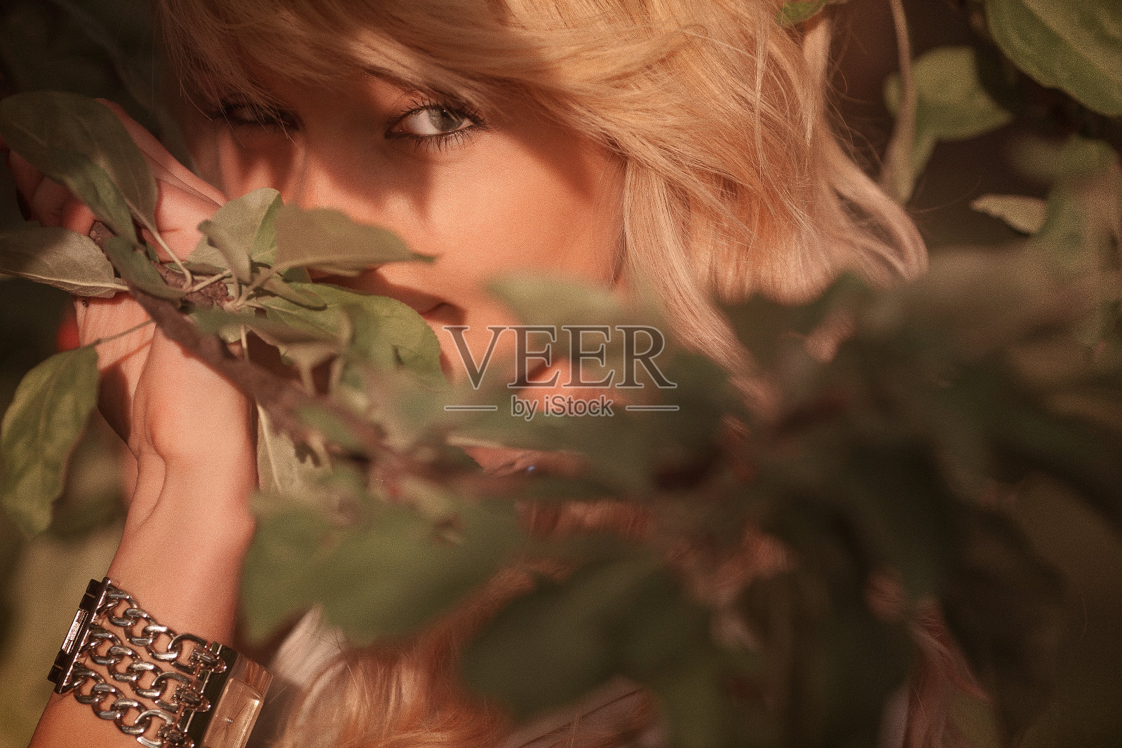 阳光明媚的女子肖像透过树叶。照片摄影图片