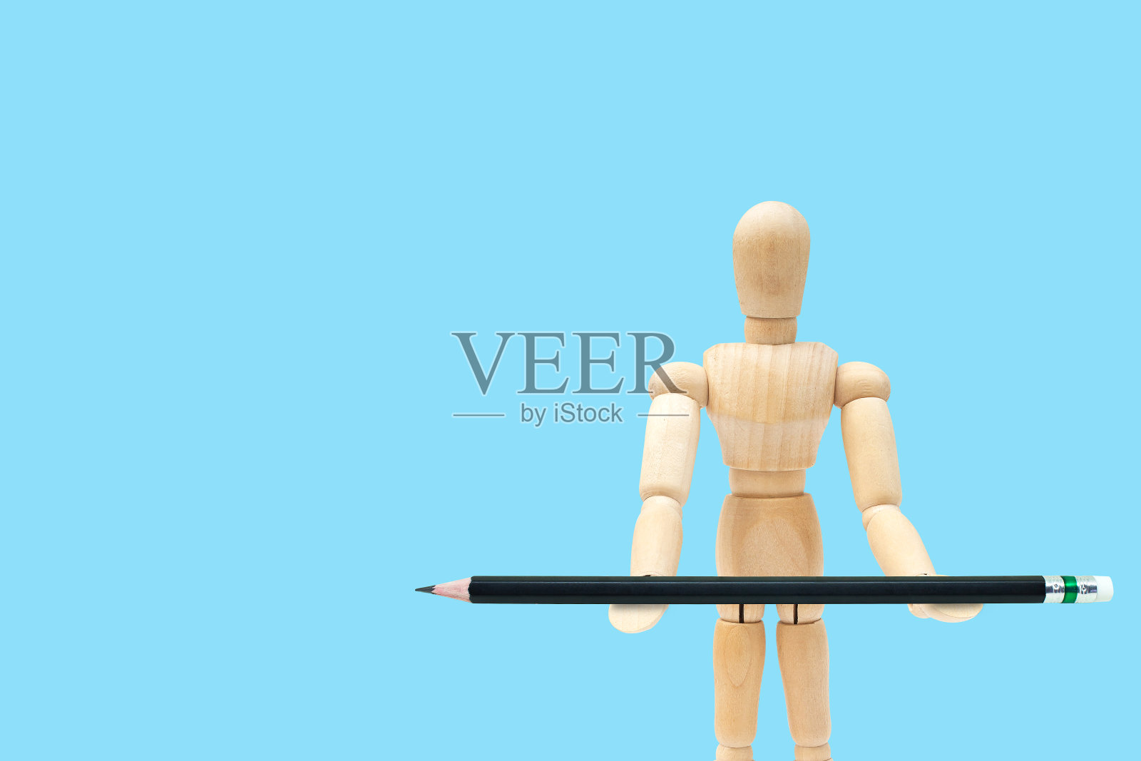 商业创意和创意概念:木制人体模型手里拿着黑色铅笔。照片摄影图片