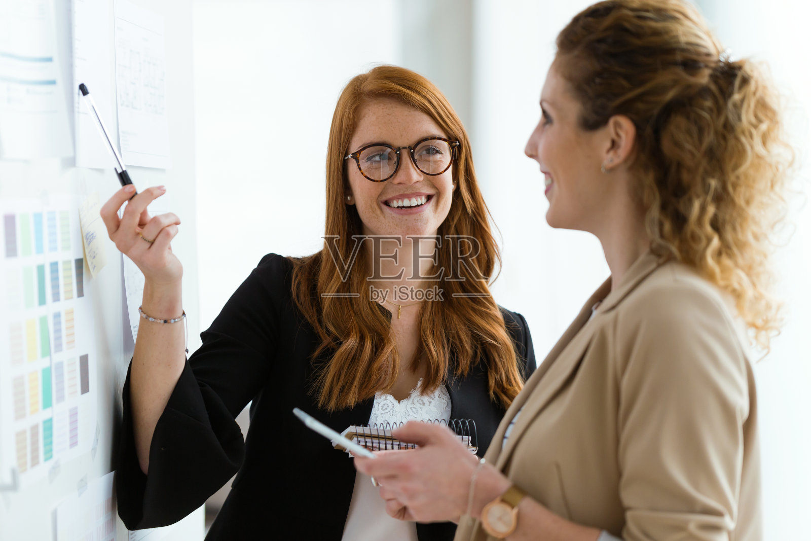 两个年轻漂亮的女商人在办公室工作。照片摄影图片