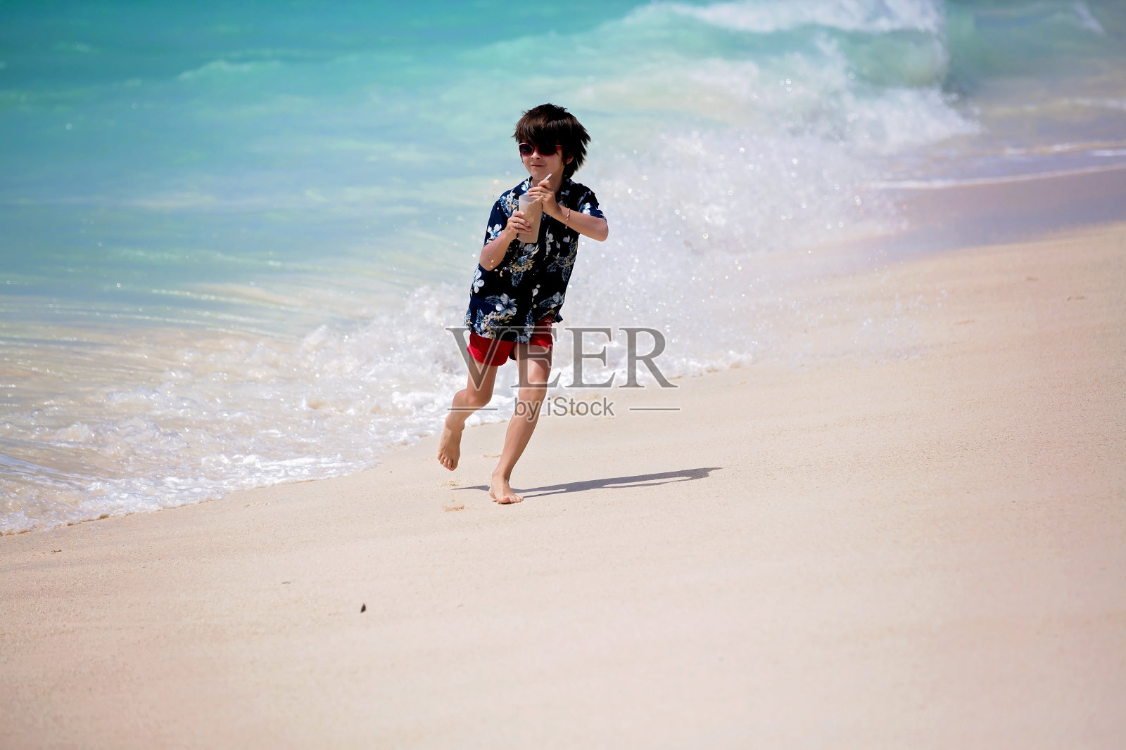 可爱的学龄前儿童，男孩们，在海边玩得很开心。孩子们兴奋地玩着海浪，游泳，愉快地溅水花照片摄影图片