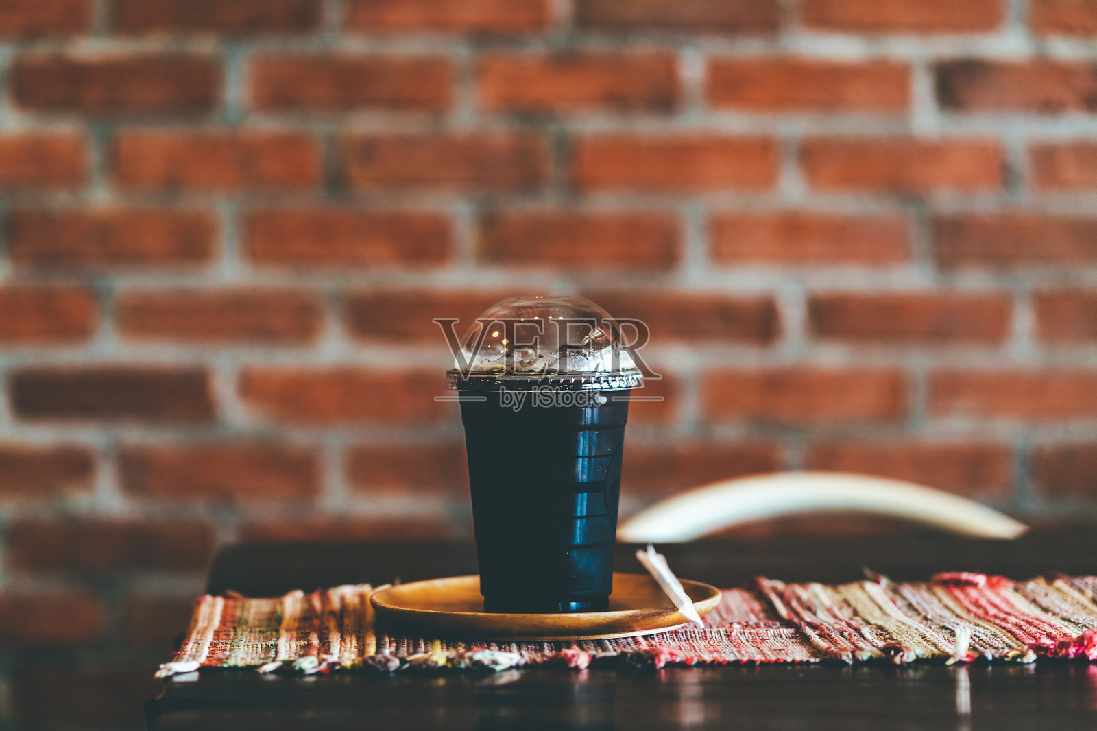 咖啡馆木桌上的美式冰咖啡。拿走塑料玻璃的杯子。照片摄影图片