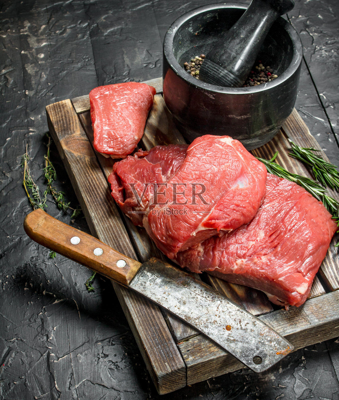 生肉。木托盘上放着新鲜的牛肉，还有香喷喷的胡椒和迷迭香。照片摄影图片