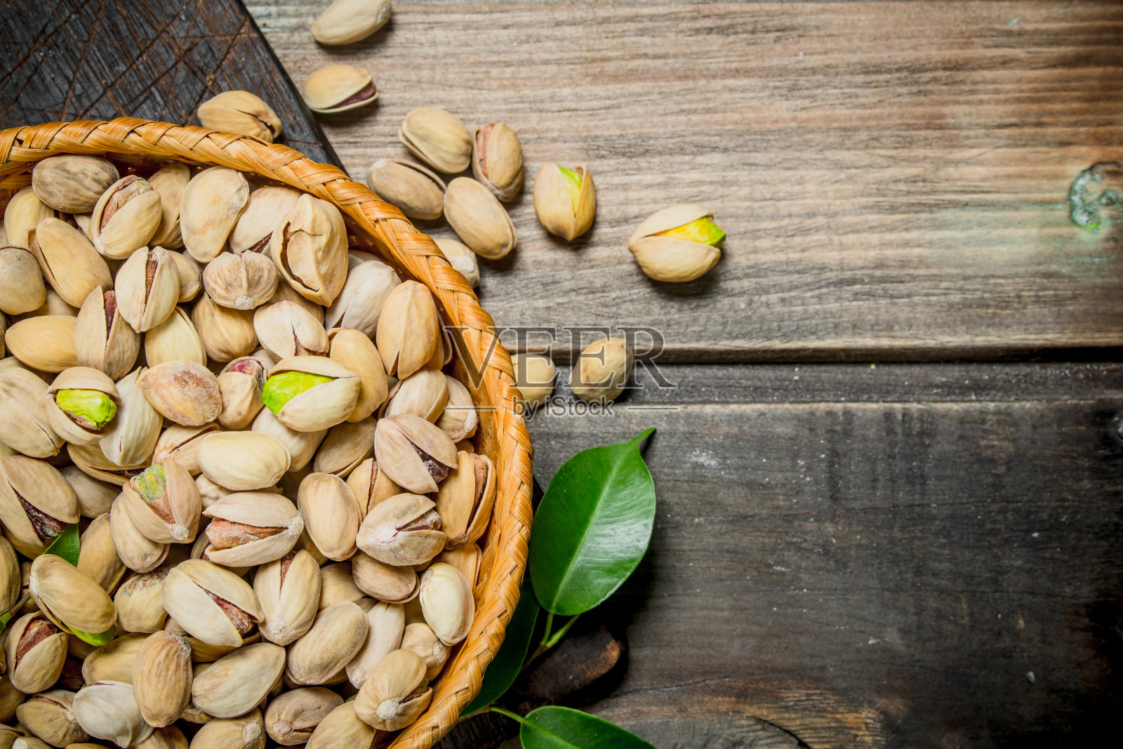 篮子里装着开心果和树叶。照片摄影图片