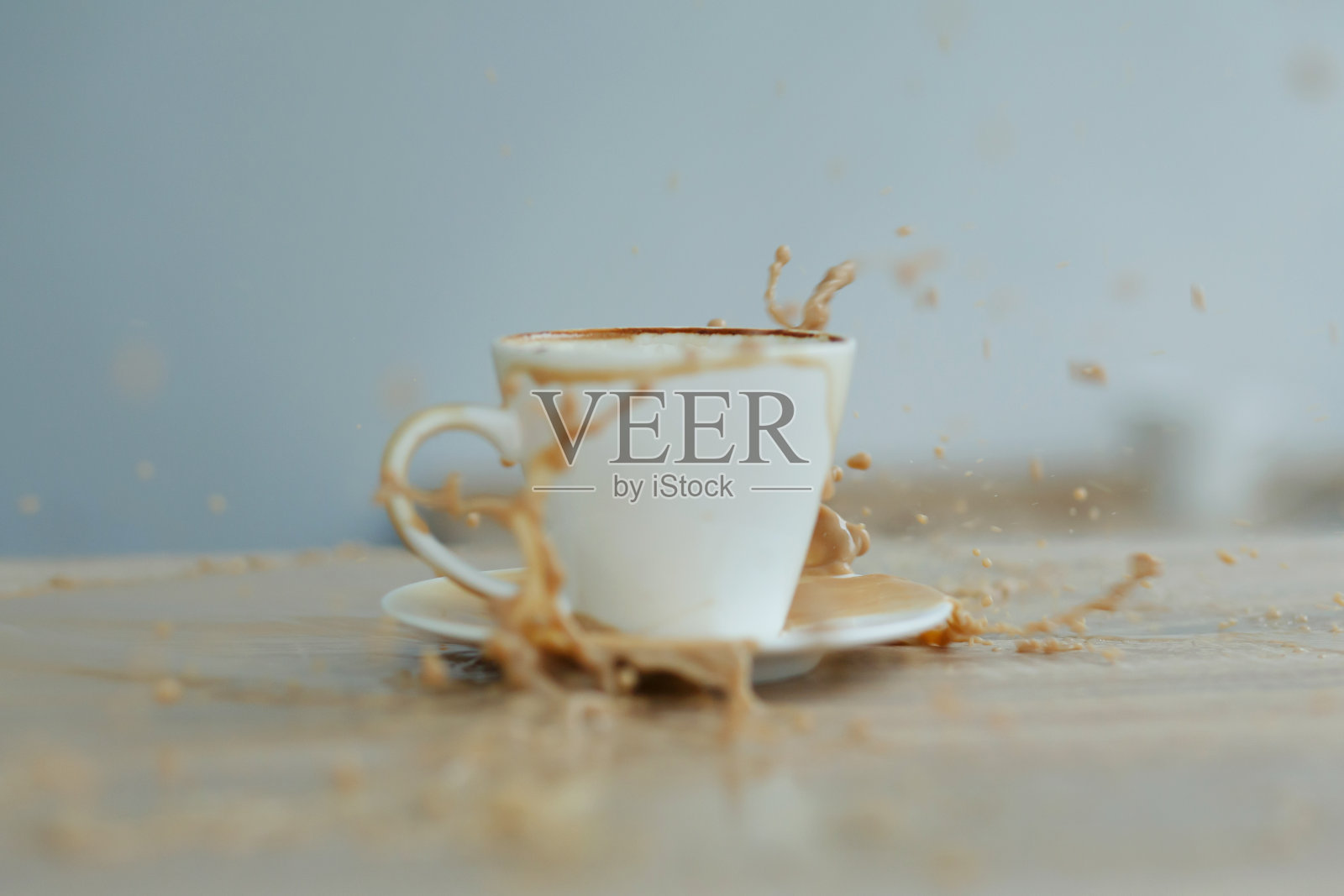 洒在木桌上的白色咖啡杯里照片摄影图片