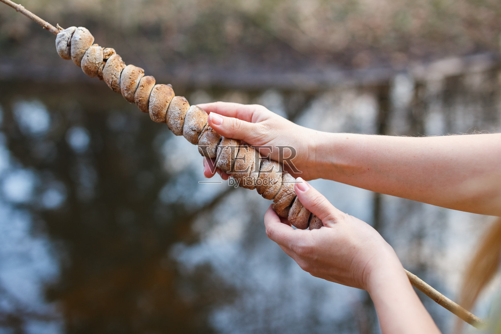 生面团上的一根棍子在森林里用火烤熟了一个女孩的手照片摄影图片