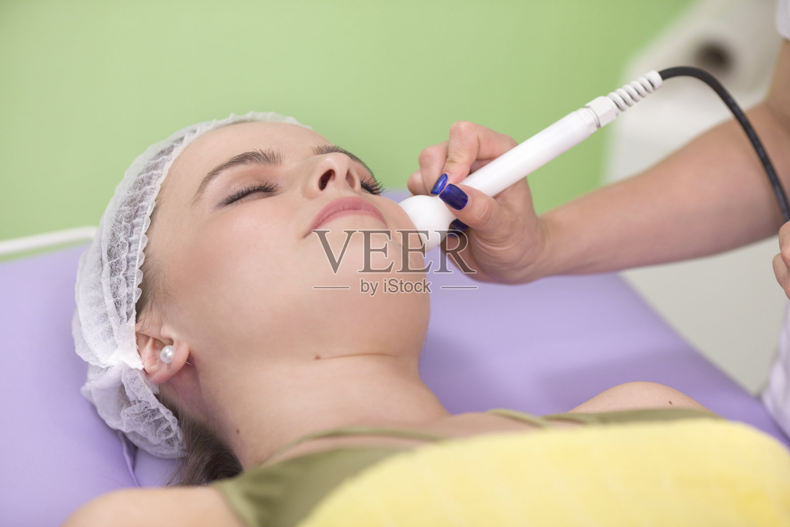 美容师为一位年轻漂亮的女士做面部真空清洁手术照片摄影图片