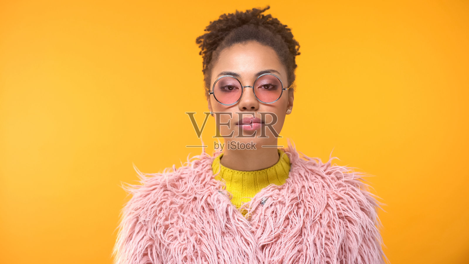 年轻时尚的女人穿着时髦的皮草和粉红色的眼镜看着镜头，时尚照片摄影图片