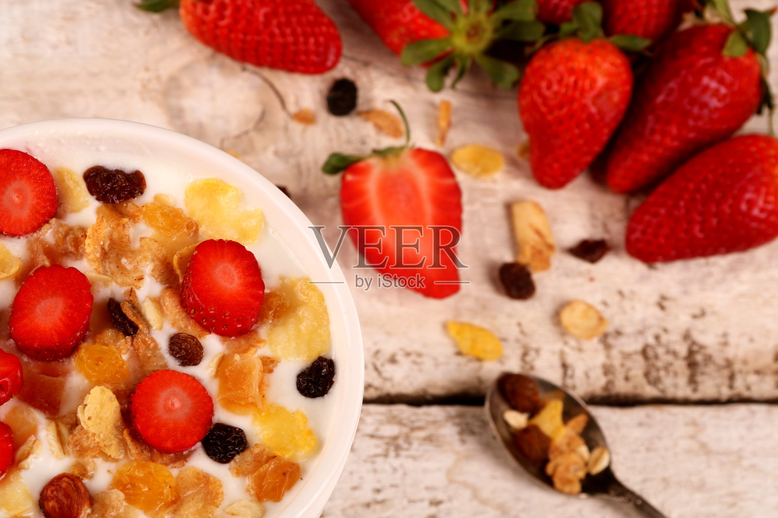 一碗草莓酸奶和格兰诺拉麦片，背景是白色的木头。照片摄影图片