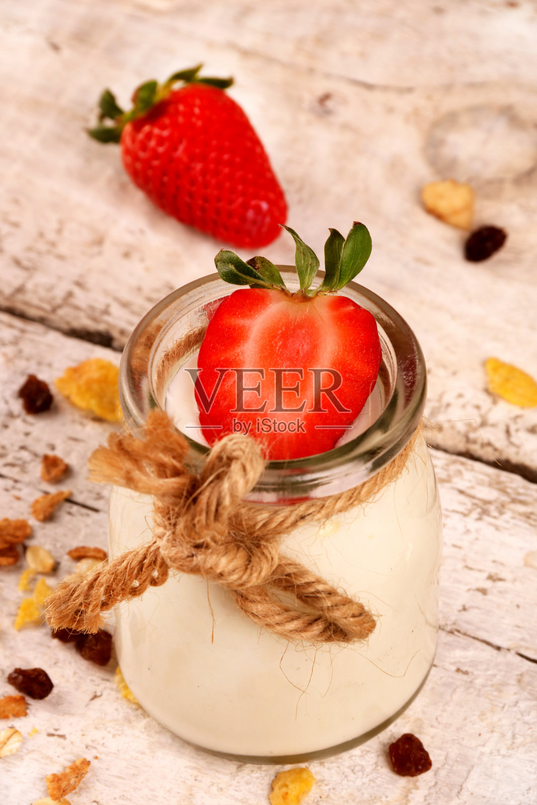 装着美味的酸奶、草莓和格兰诺拉麦片的罐子，放在白色的木桌上照片摄影图片