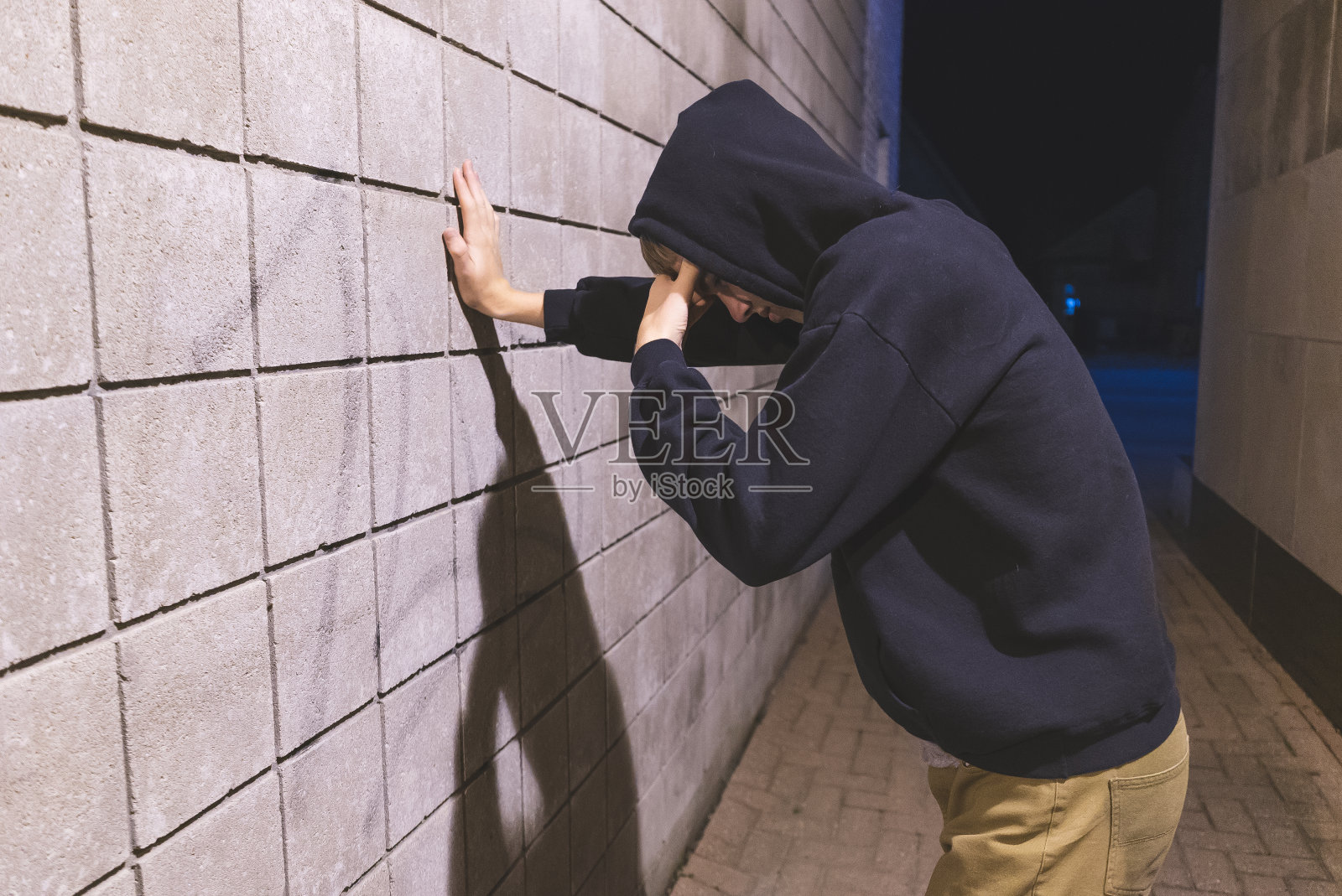 悲伤的少年站在巷子里。照片摄影图片