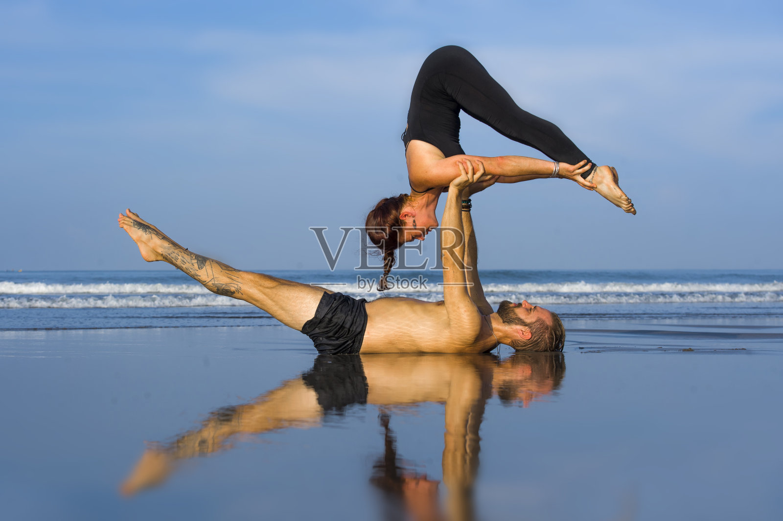 年轻迷人和美丽的杂技演员夫妇练习杂技瑜伽集中保持平衡练习瑜伽在海滩上放松和冥想的概念和健康的生活方式照片摄影图片