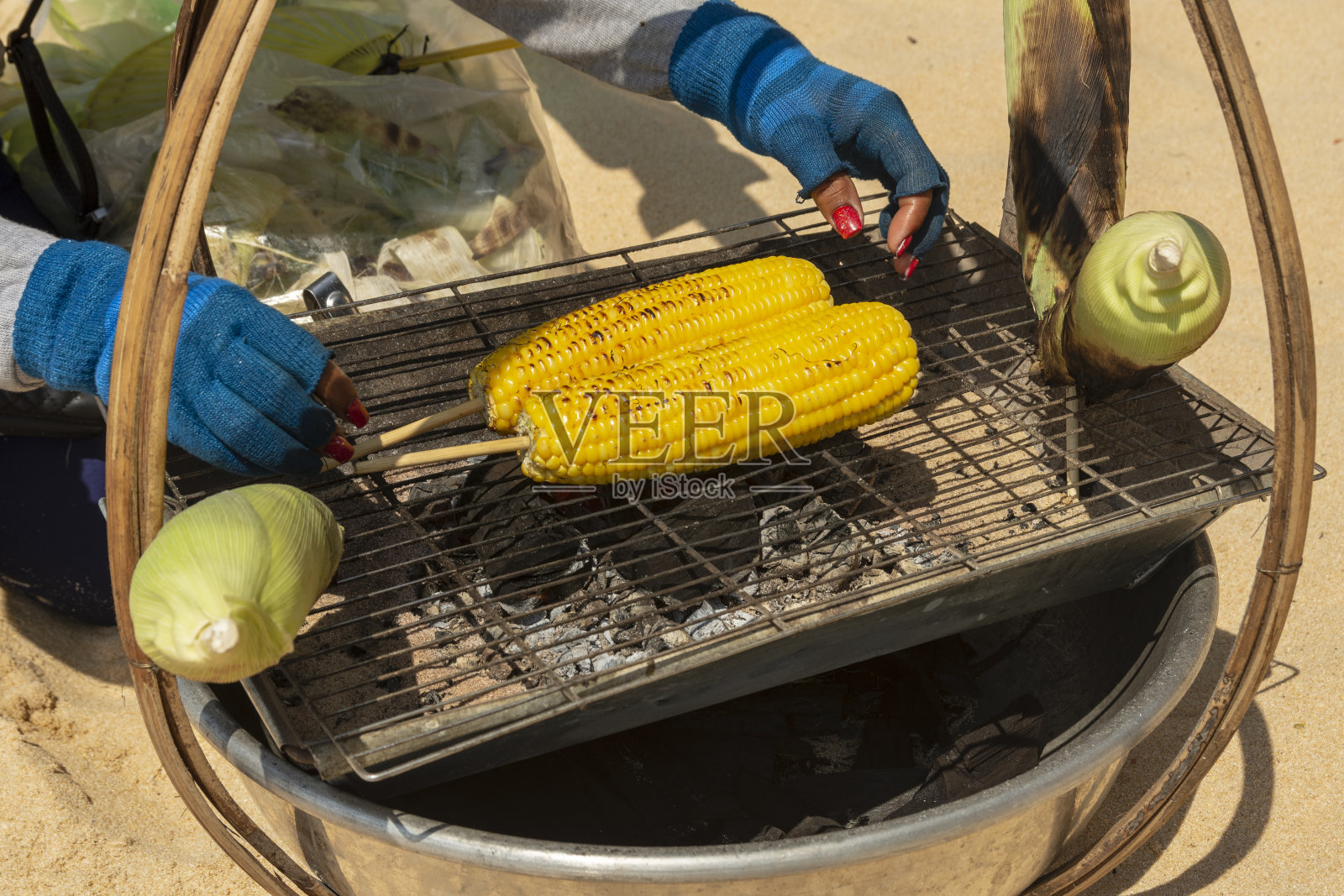 带两个玉米棒的便携式烤架几乎可以吃了。照片摄影图片