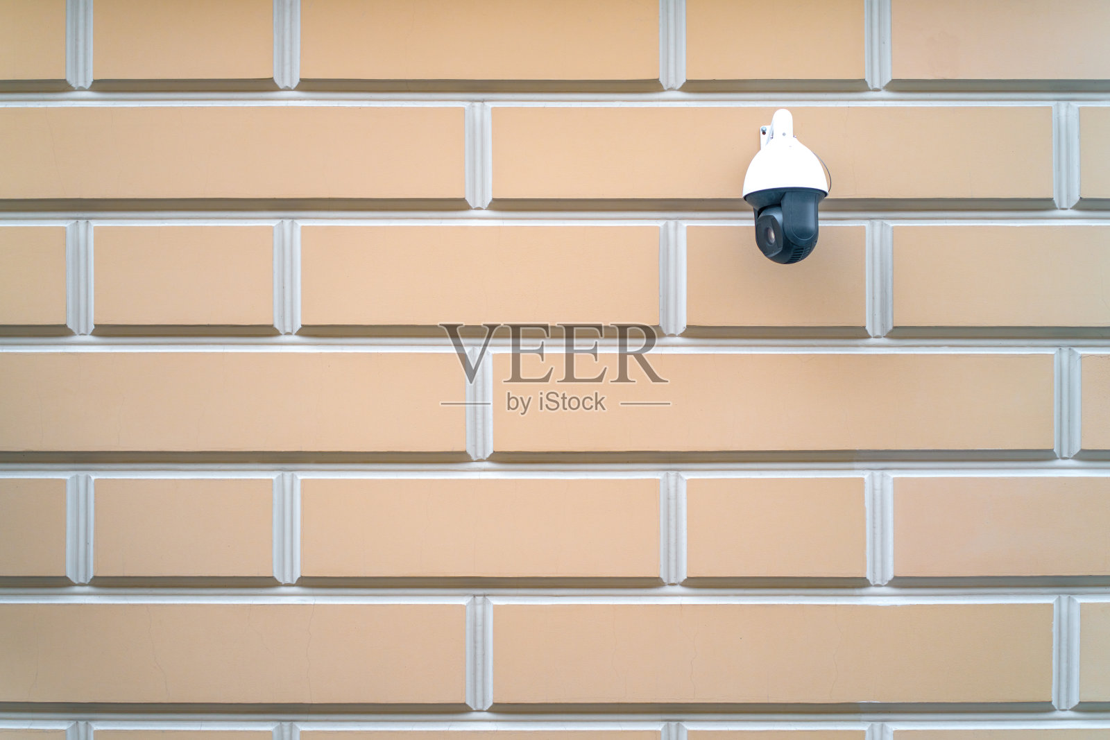 闭路电视的监控摄像头在一栋建筑的墙上黑色旋转。外部安全。背景是一堵干净的墙壁，墙上布满了锈迹。照片摄影图片