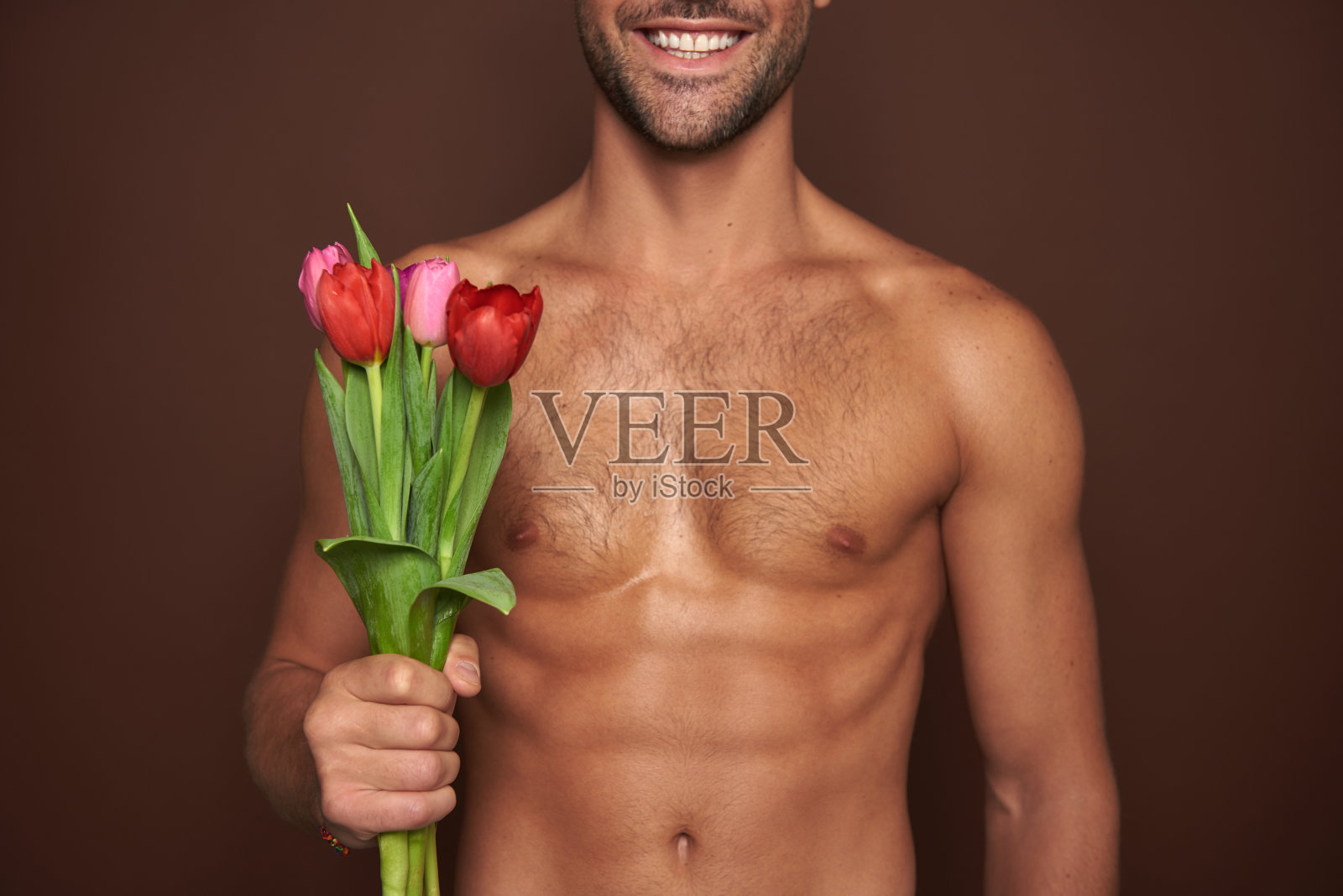 微笑的肌肉男子与郁金香束照片摄影图片