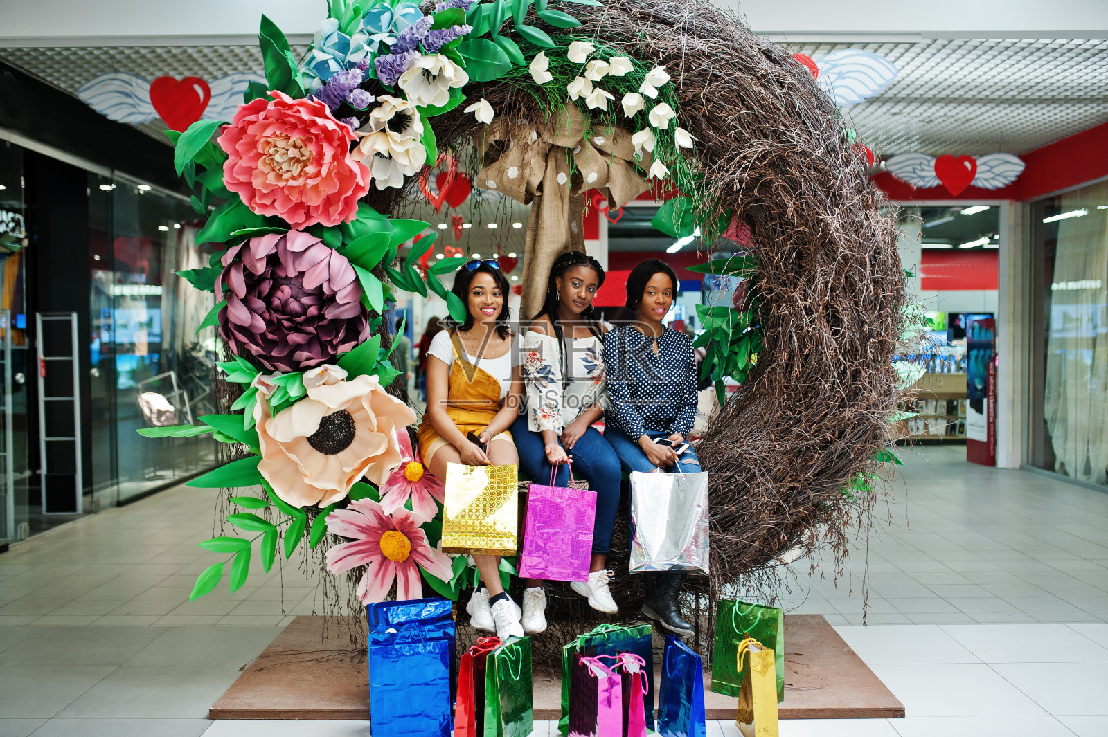 漂亮的三个穿着考究的非洲裔美国女孩拿着彩色购物袋照片摄影图片