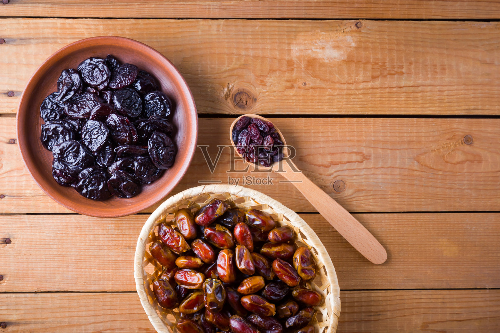 木色背景上的干枣和李子。神圣的斋月，概念。公义的穆斯林的生活方式。饥饿。干果:放在木板上的枣子、李子和葡萄干照片摄影图片