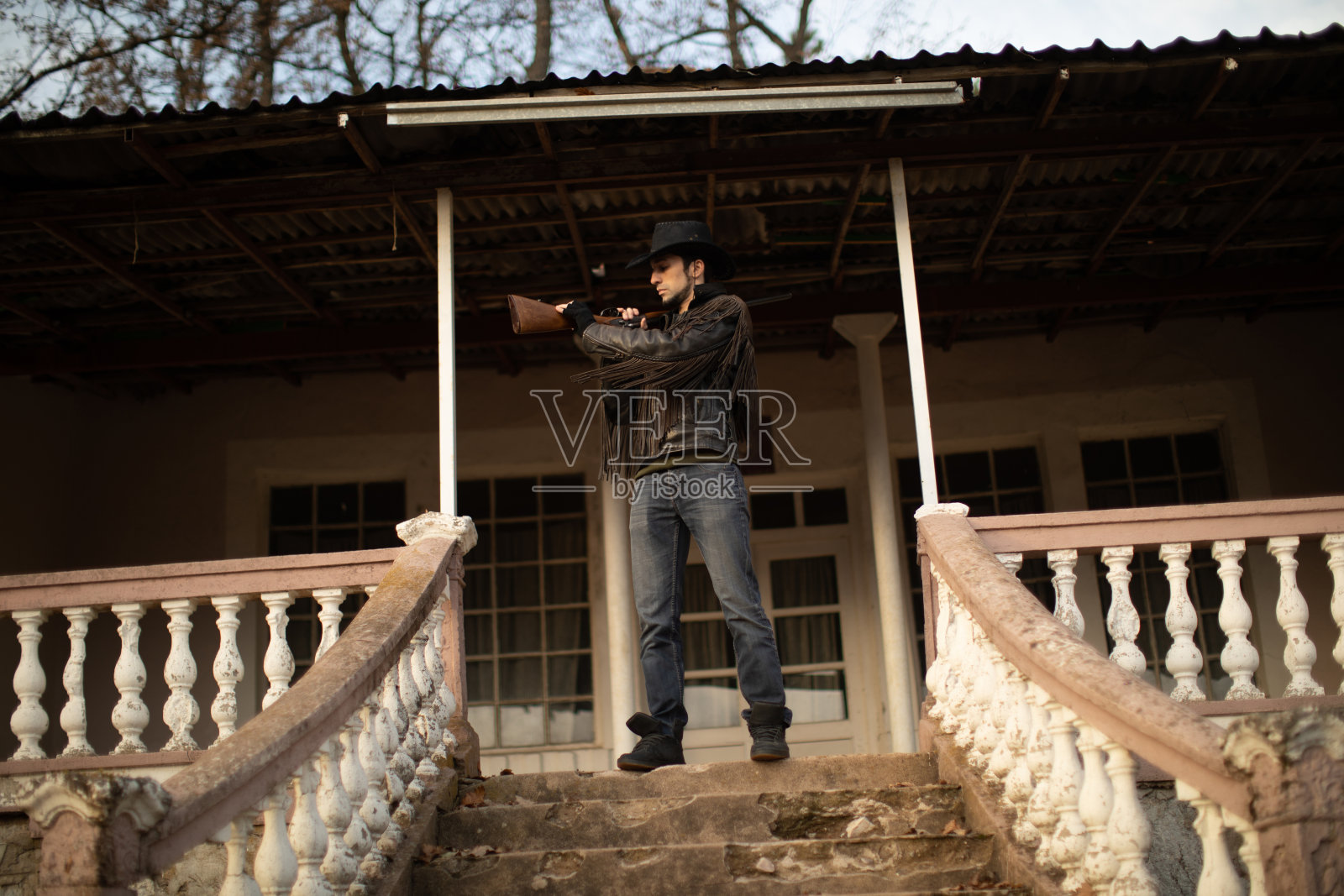 勇敢的牛仔拿着步枪站在房子前面照片摄影图片