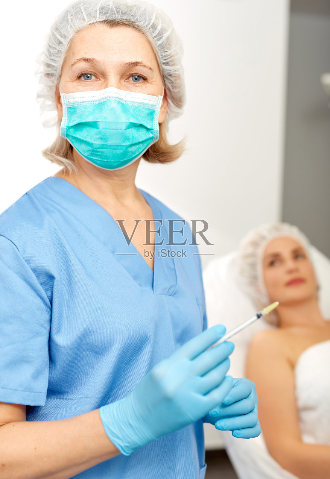 美容师在防护纱布面罩与注射器照片摄影图片