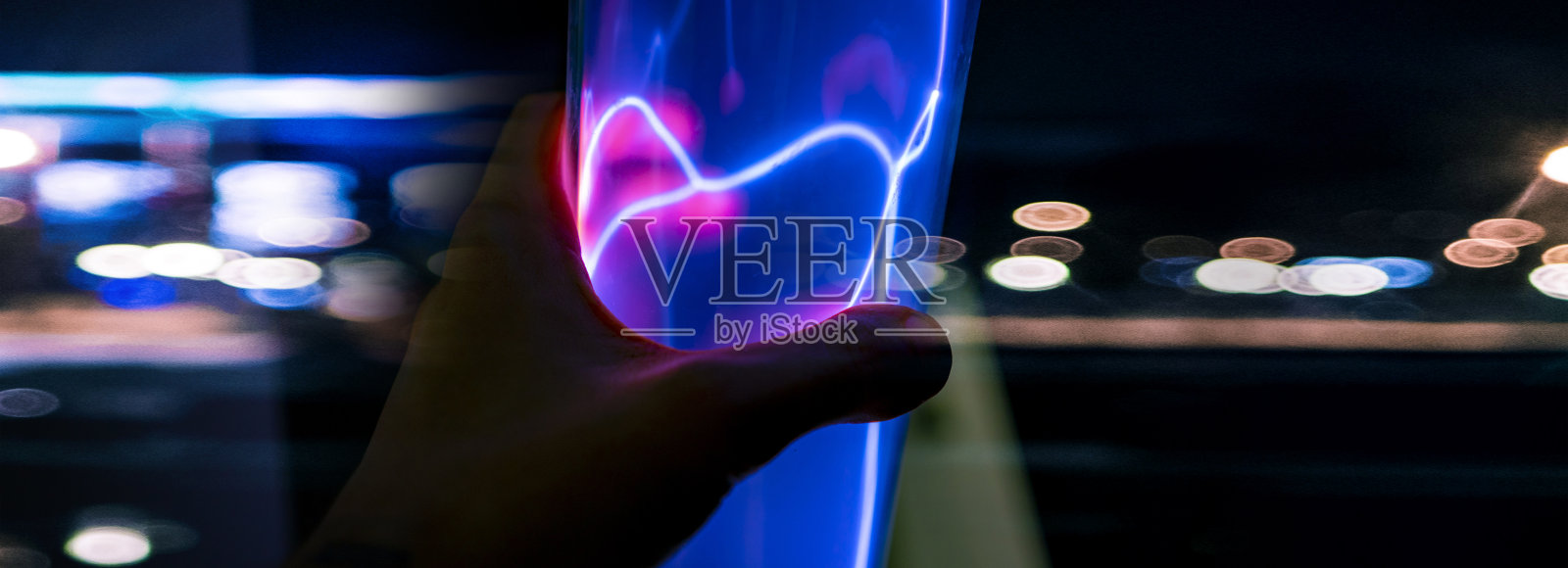 近距离用手触摸发光玻璃灯泡与等离子体照片摄影图片