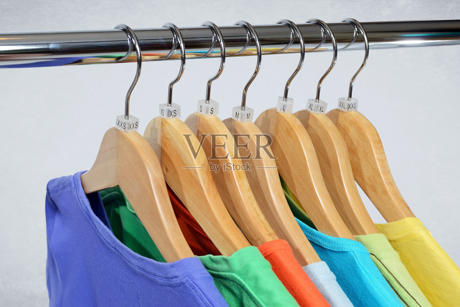 不同颜色的t恤挂在封闭架上照片摄影图片