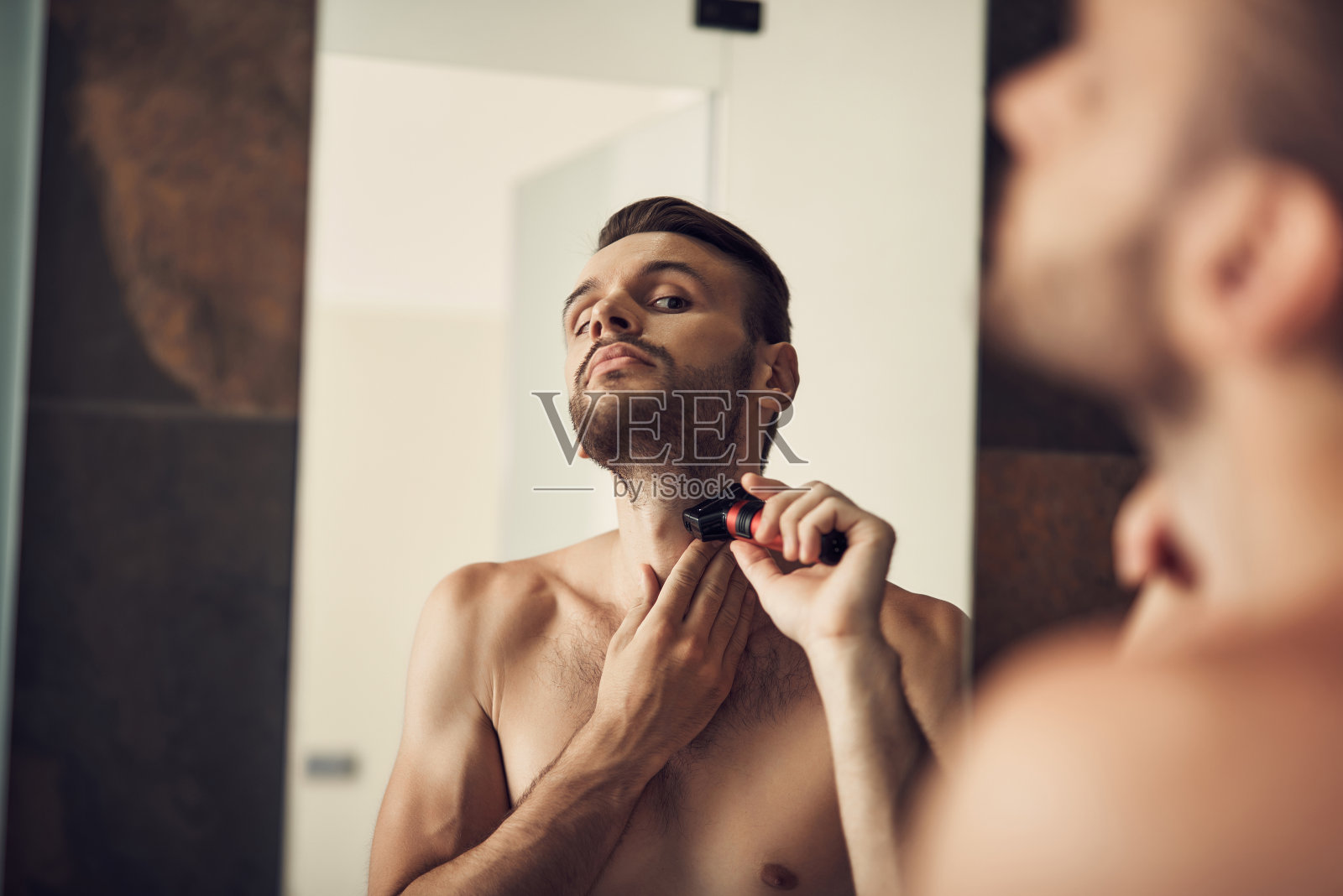 长胡子的帅哥在浴室里刮胡子照片摄影图片