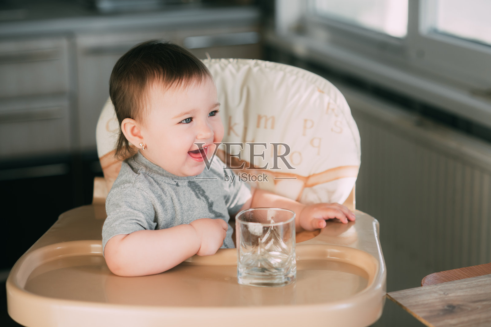 可爱的小女孩坐在婴儿椅上喝水照片摄影图片