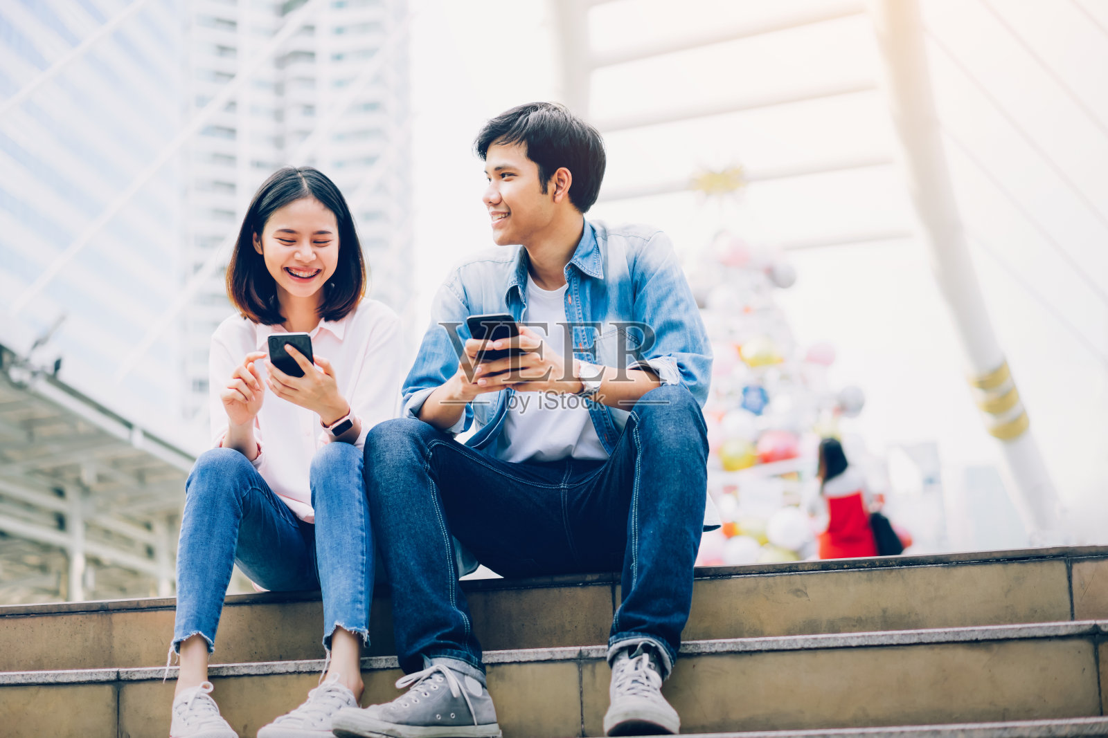 年轻人正在使用智能手机，坐在空闲时间微笑。技术概念照片摄影图片