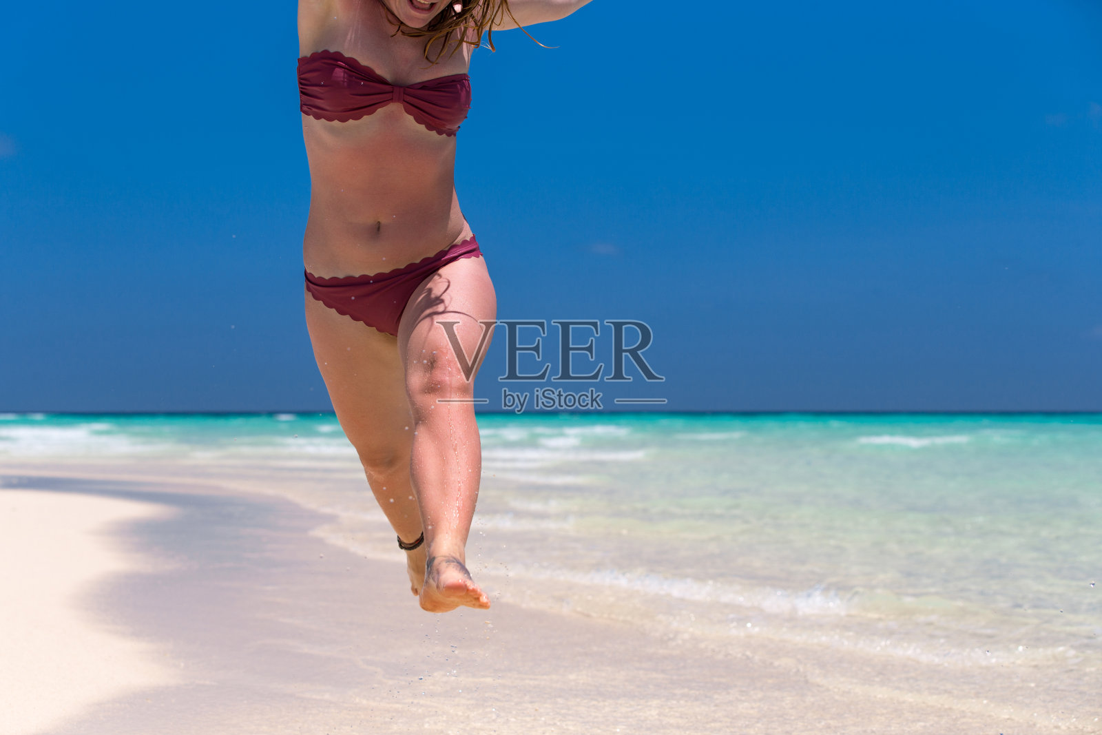 穿着比基尼的成年女子在田园诗般的沙滩上跑步照片摄影图片