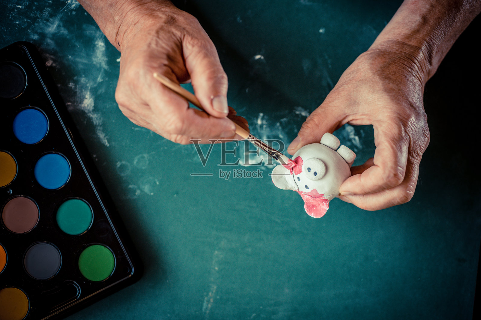 年长者双手近距离地画着小泥猪照片摄影图片