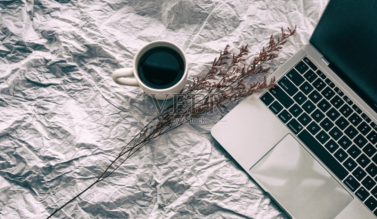 陶瓷咖啡杯的抽象艺术设计背景放在干花和笔记本电脑旁，四周模糊的灯光照片摄影图片