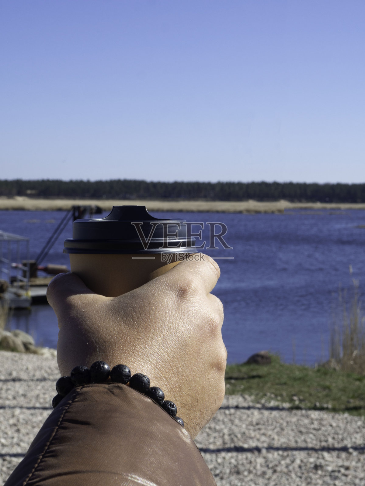 男人拿着一杯咖啡或其他热饮。背景中模糊的街道照片摄影图片