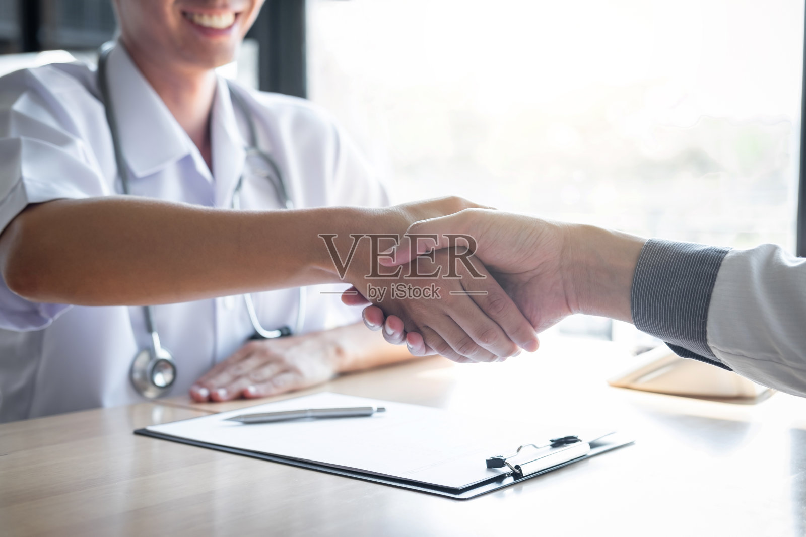 医生在推荐治疗后与患者握手祝贺，同时讨论解释他的症状，并建议诊断健康、保健和援助的概念照片摄影图片