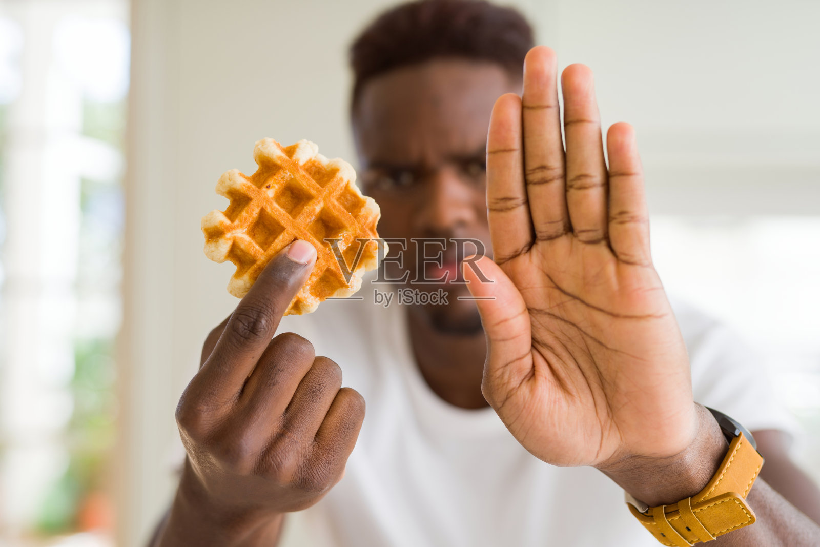 非裔美国人吃甜的比利时华夫饼张开手做停止手势与严肃和自信的表情，防御手势照片摄影图片