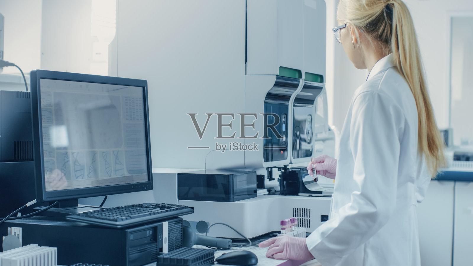 女性研究科学家工作与医学分析机器的试管与血液样本。科学家在创新药物遗传研究实验室工作。照片摄影图片