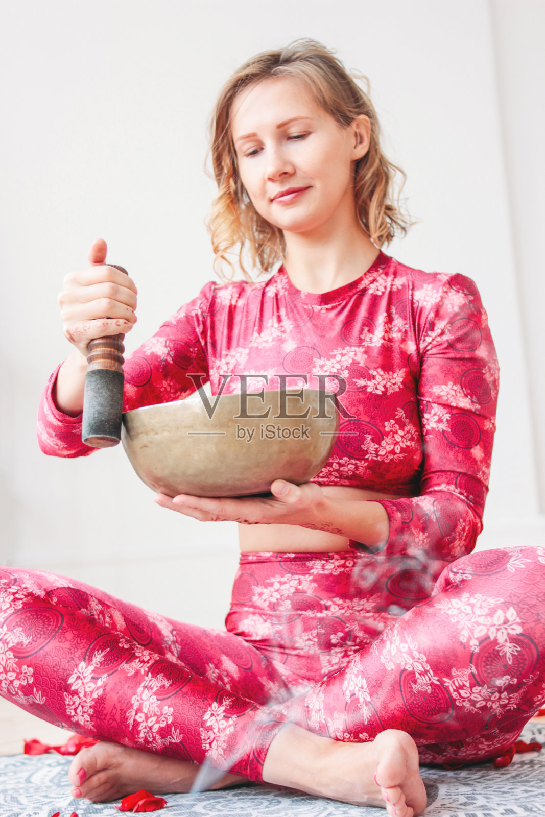 年轻女子在铜制的藏族歌唱碗上弹奏。声音疗法和冥想照片摄影图片