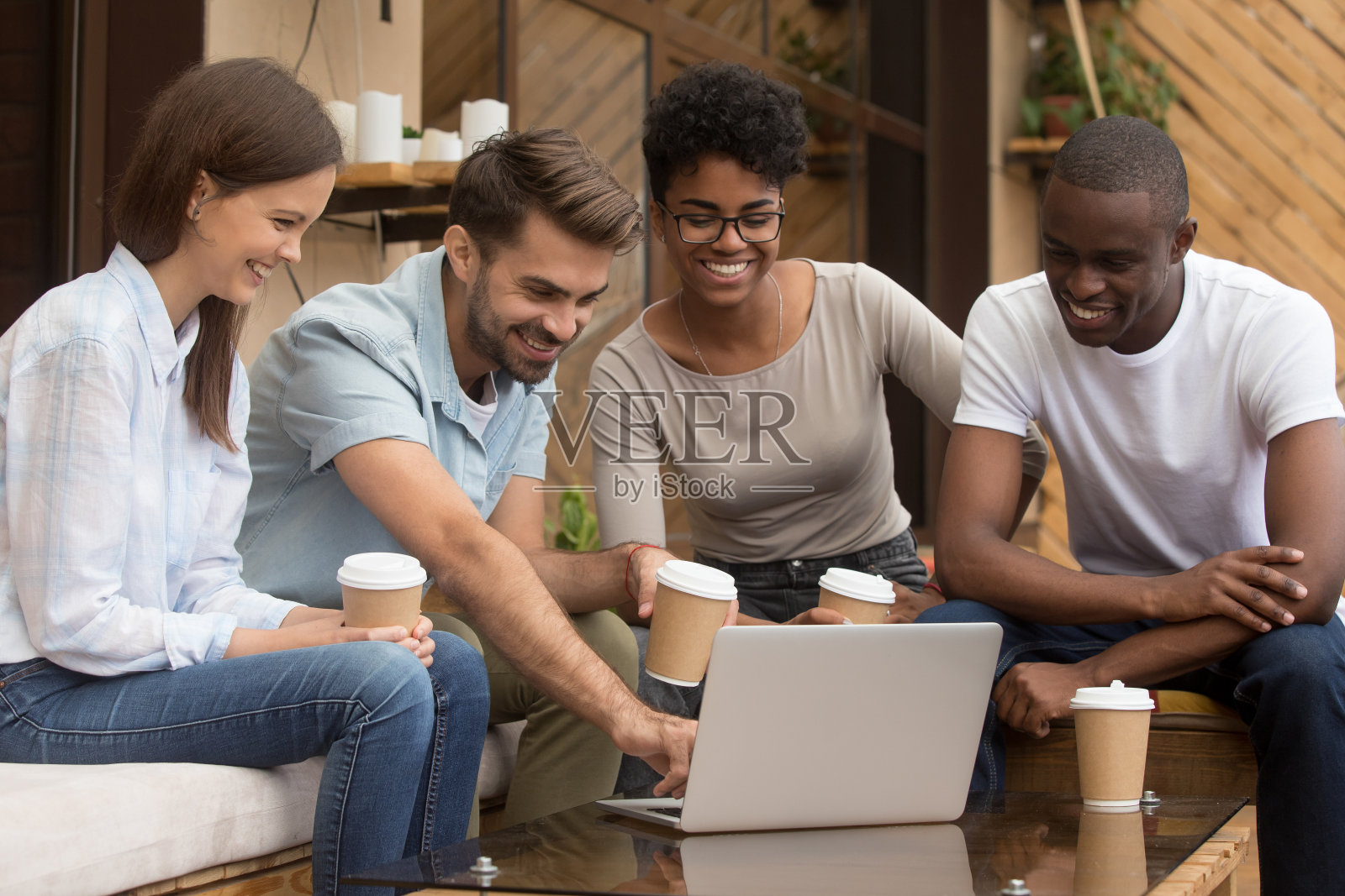 快乐的家伙在咖啡馆外用笔记本电脑给不同的朋友看视频照片摄影图片