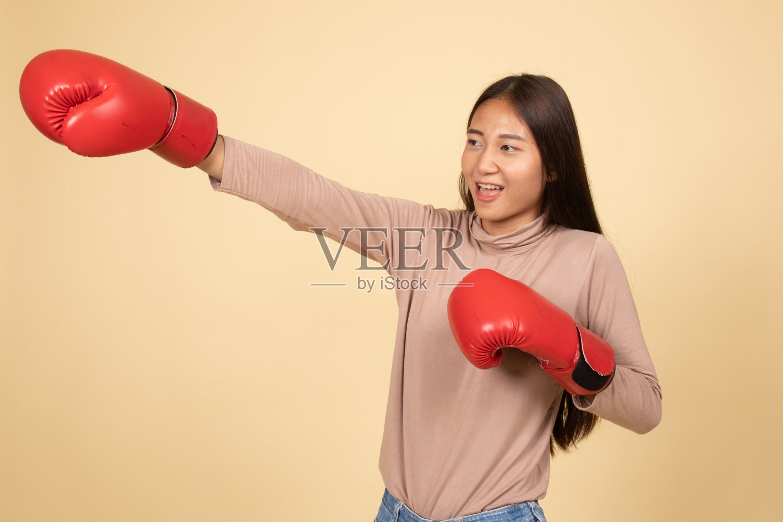 戴着红色拳击手套的年轻亚洲女子。照片摄影图片