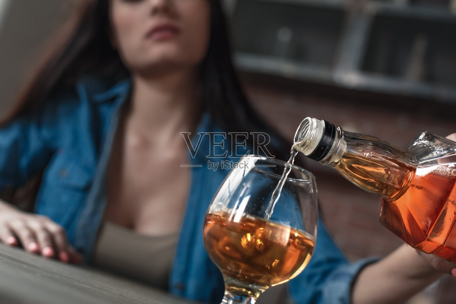 年轻女人因酗酒产生社会问题，坐着倒酒特写照片摄影图片