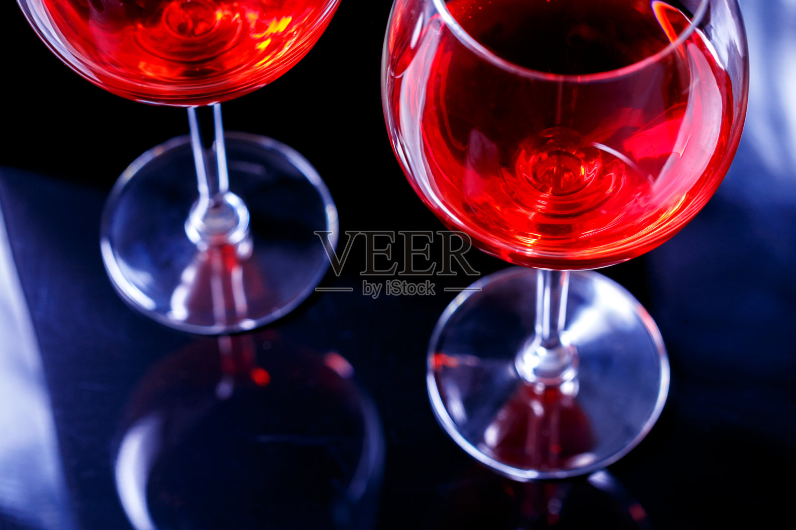 夜店里的两杯红酒，黑色背景下的倒影。照片摄影图片