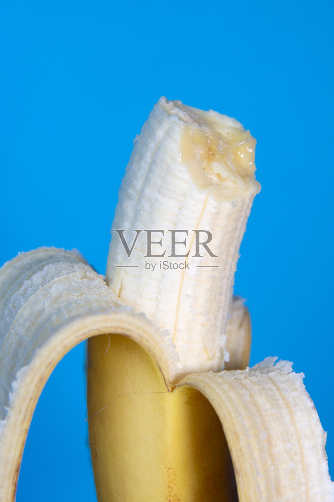 蓝色背景上一半吃剥了皮的香蕉的特写照片摄影图片